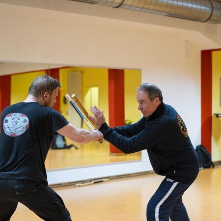 Zwei Männer mit Escrima-Stöcken üben Kampfsporttechniken