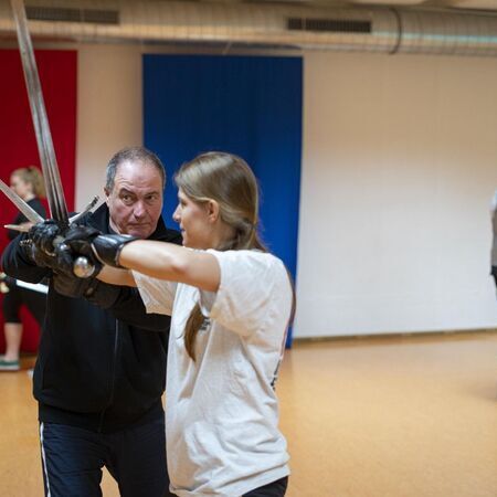 Eine Frau und ein Mann üben Schwertkampftechniken miteinander