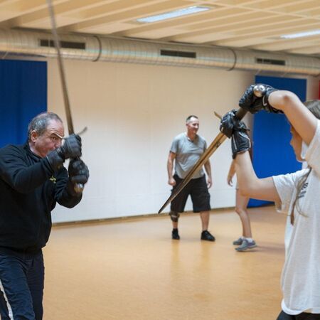 Eine Frau und ein Mann üben Schwertkampftechniken miteinander