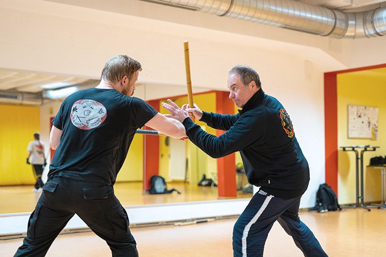 Zwei Männer üben in einem Fitnessstudio Kampfsporttechniken