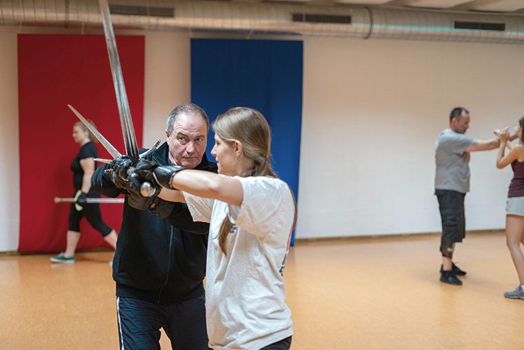 Ein Mann und eine Frau praktizieren Schwertkampf in einem Sportstudio