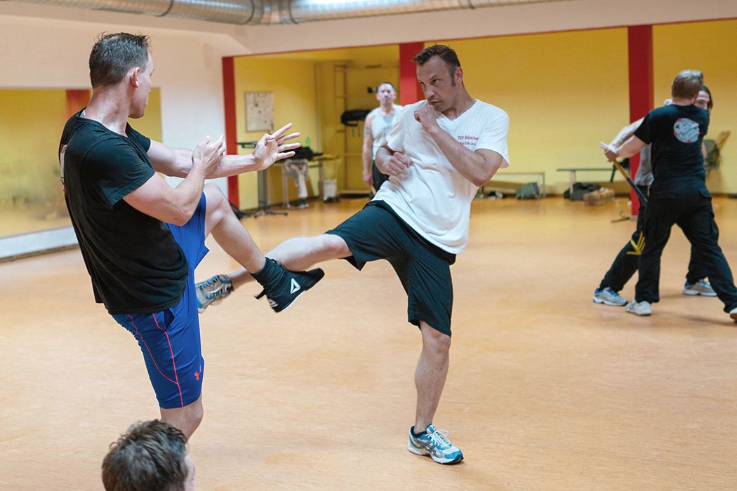 Zwei Männer im Fitnessstudio führen martialische Kicks aus