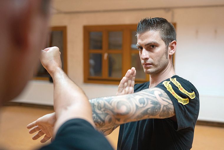 Ein tätowierter Mann demonstriert martialische Techniken in Aktion