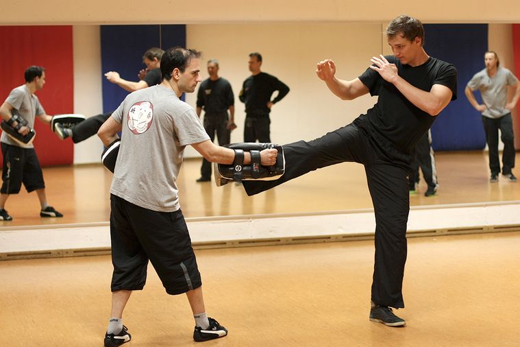 Ein Mann in schwarzem Shirt und schwarzen Hosen übt eine Kampfkunsttechnik